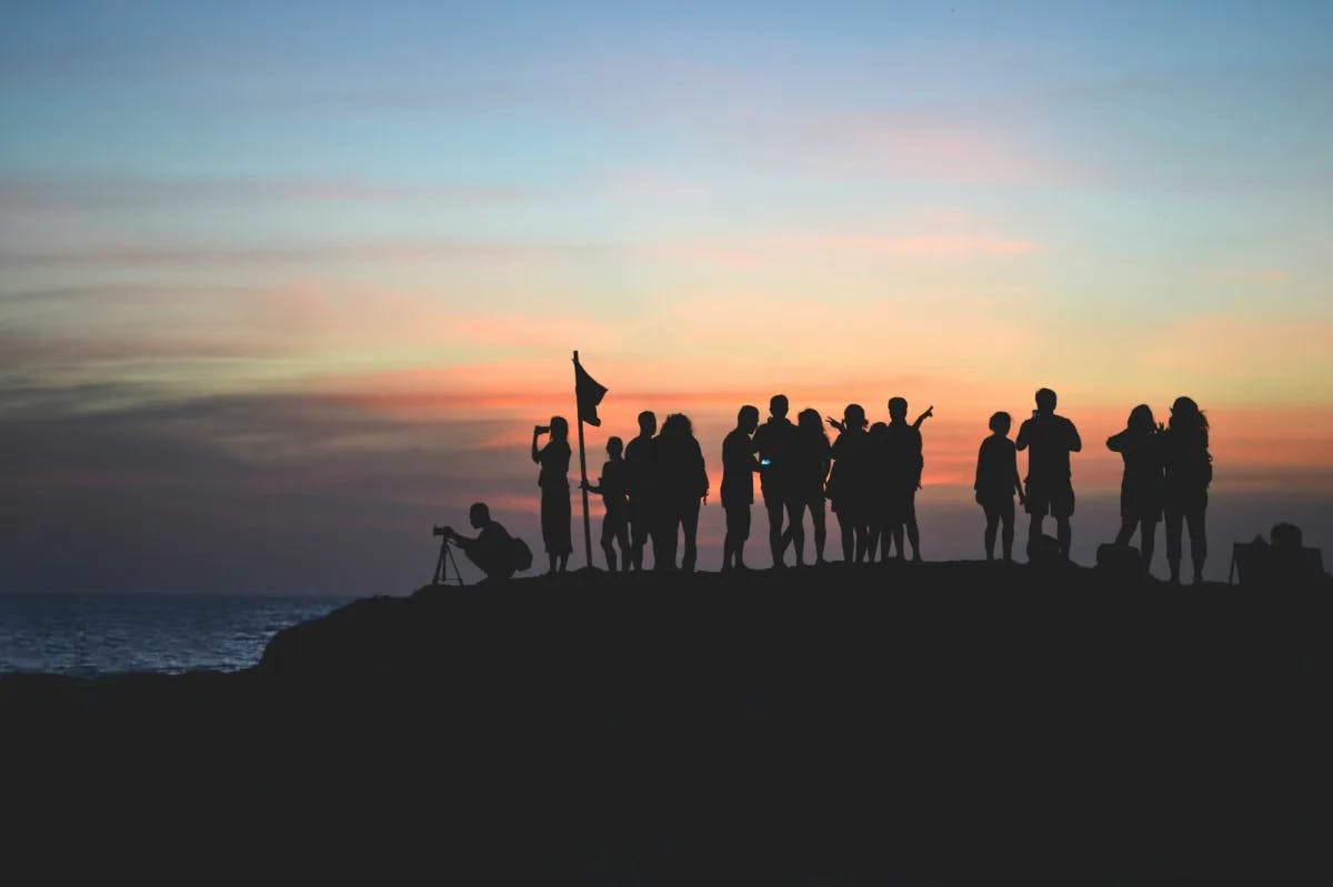 A large group of travelers taking in the view at sunset at Tanah Lot Temple in Indonesia
