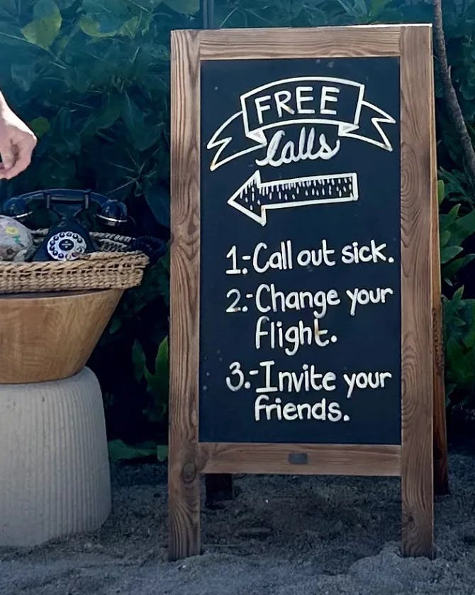 A chalk board that reads 'free calls' with a telephone on a table next to it