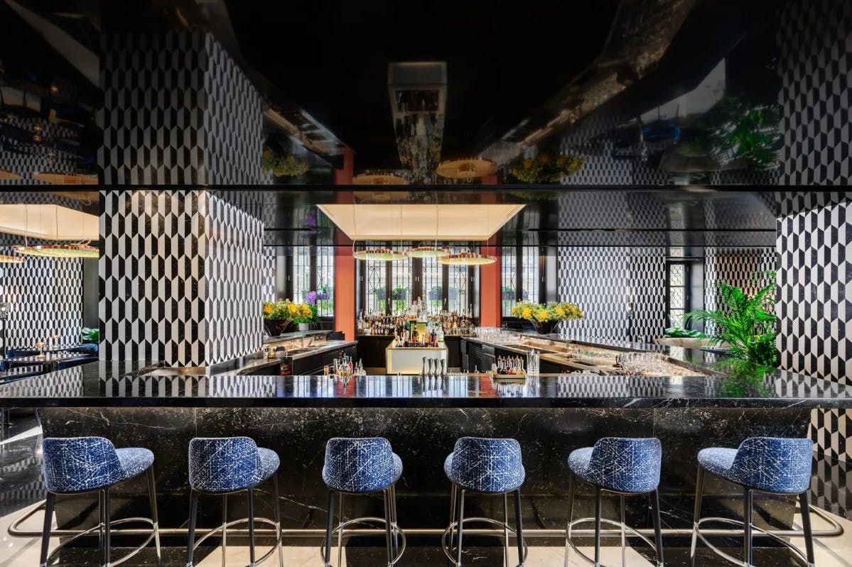 a sexy bar with blue stools and a black shiny countertop
