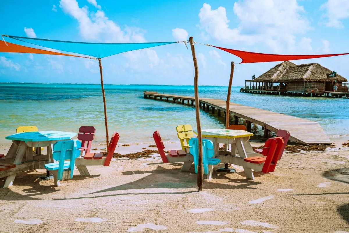 A picture of colorful beach chairs and tables set near the beach during the daytime.