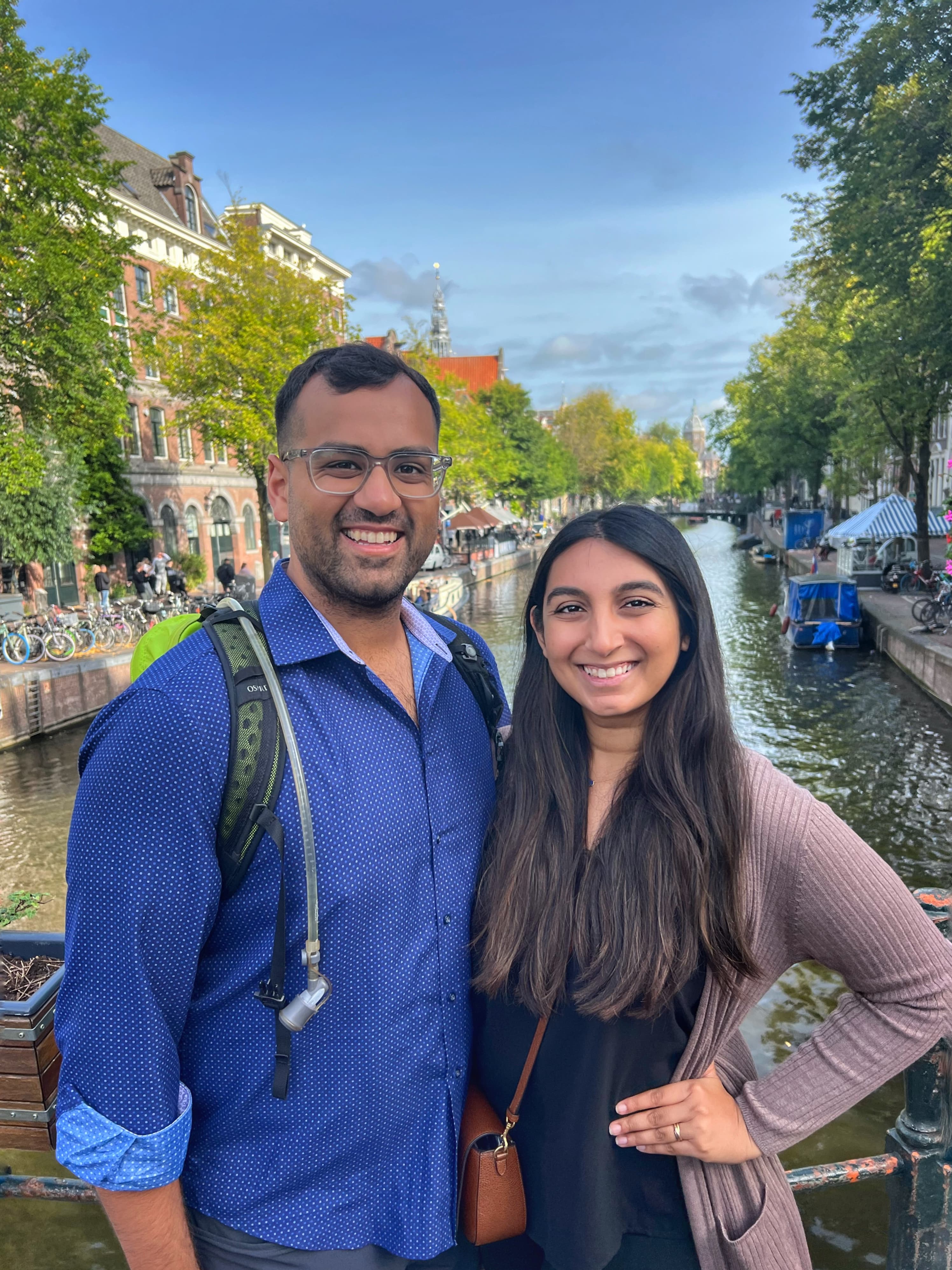 Khushbu and partner standing on a bridge and posing in front of a European canal.