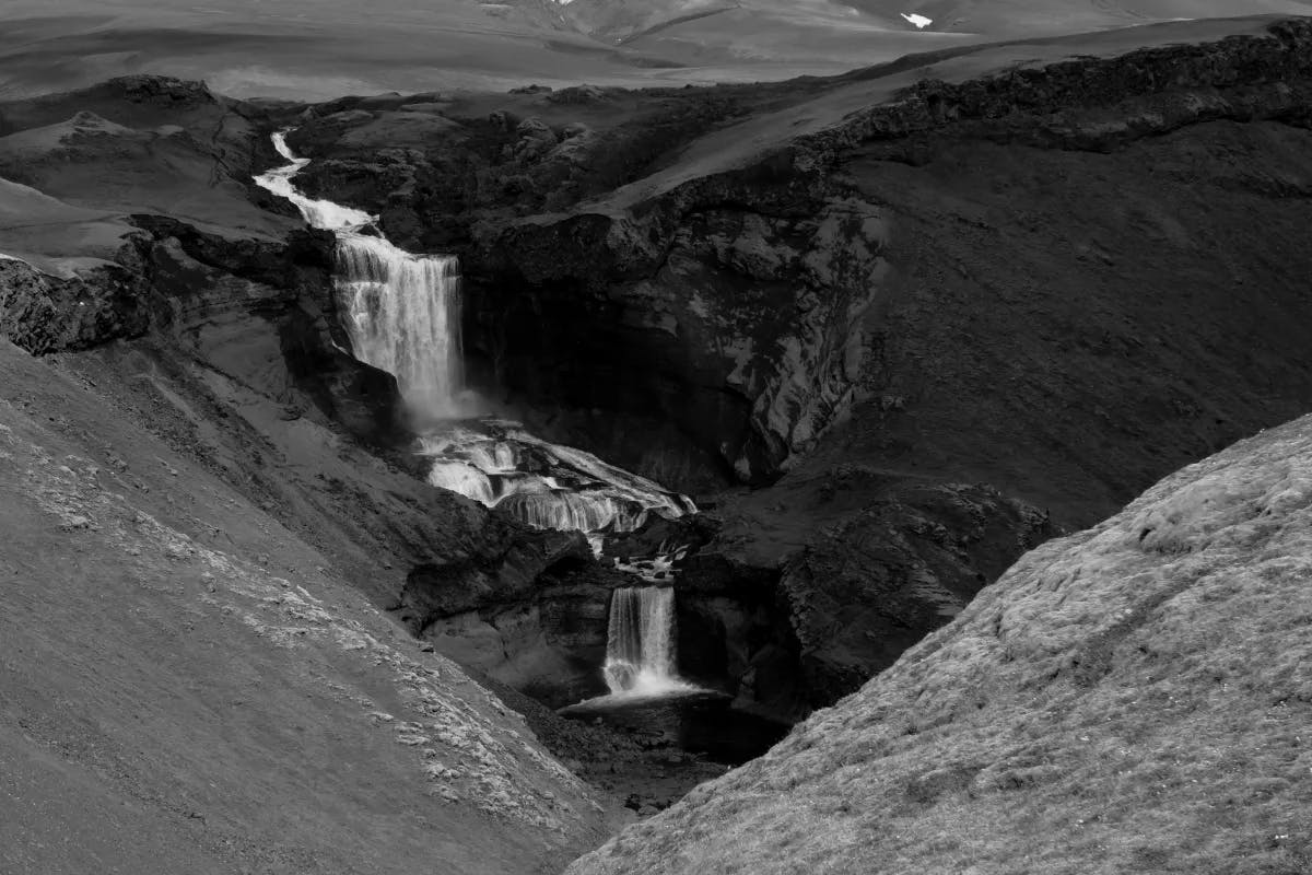 A black and white photo of a waterfall large waterfall. 