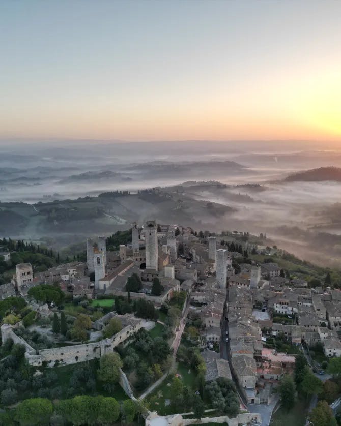 An aerial view of a lovely town with a sunset and light hints of fog giving a peaceful and romantic vibe.