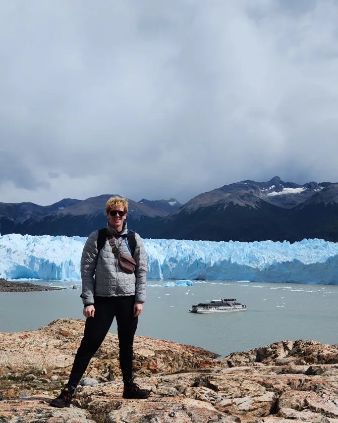 Lucas standing on rocks in front of glaciers on a cloudy day