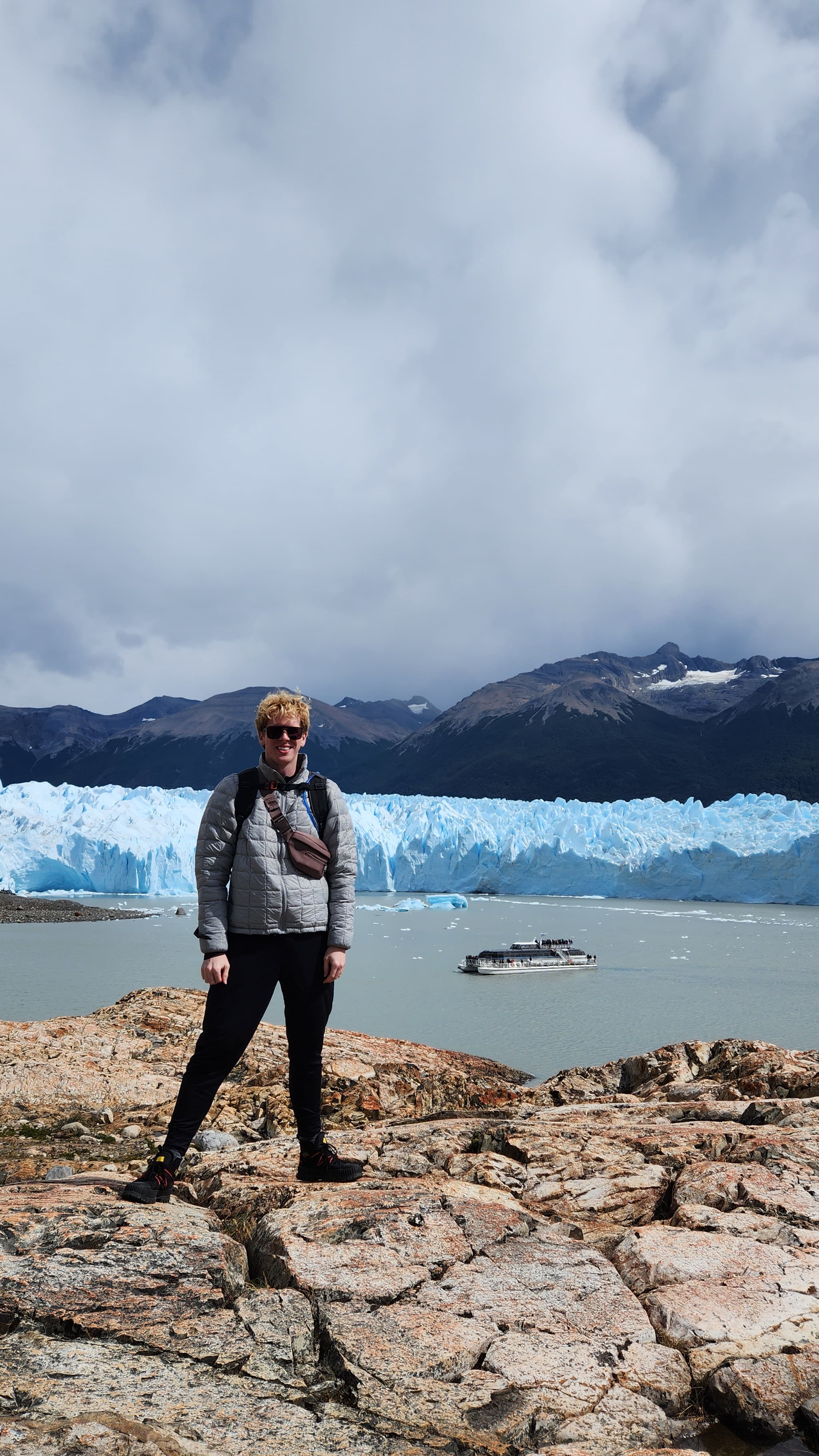 Lucas standing on rocks in front of glaciers on a cloudy day