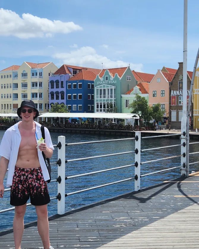 Lucas standing on a boardwalk with water and colorful buildings in the background