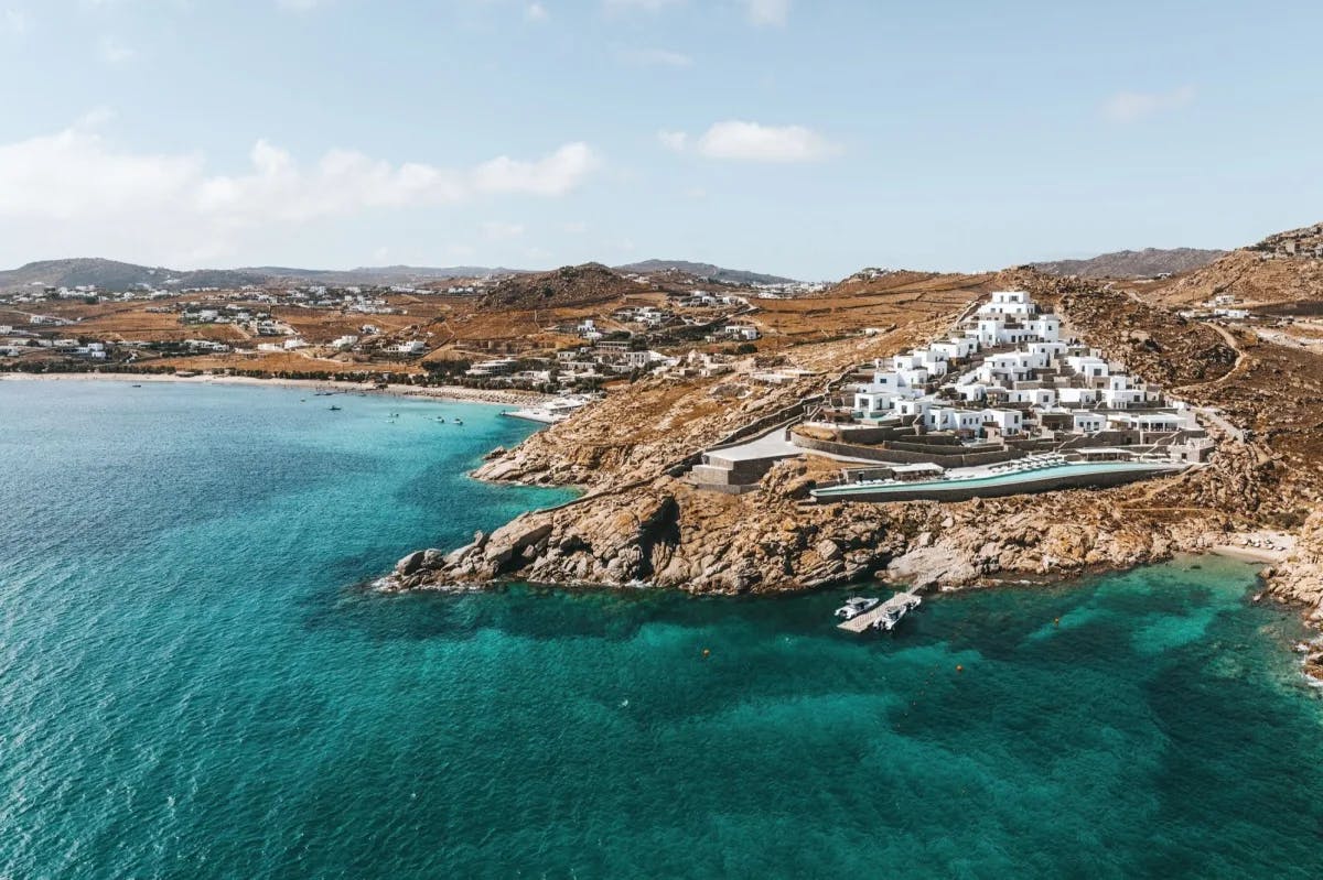 Sapphire seas contrast with rocky hills and the whitewashed buildings of Cali Mykonos