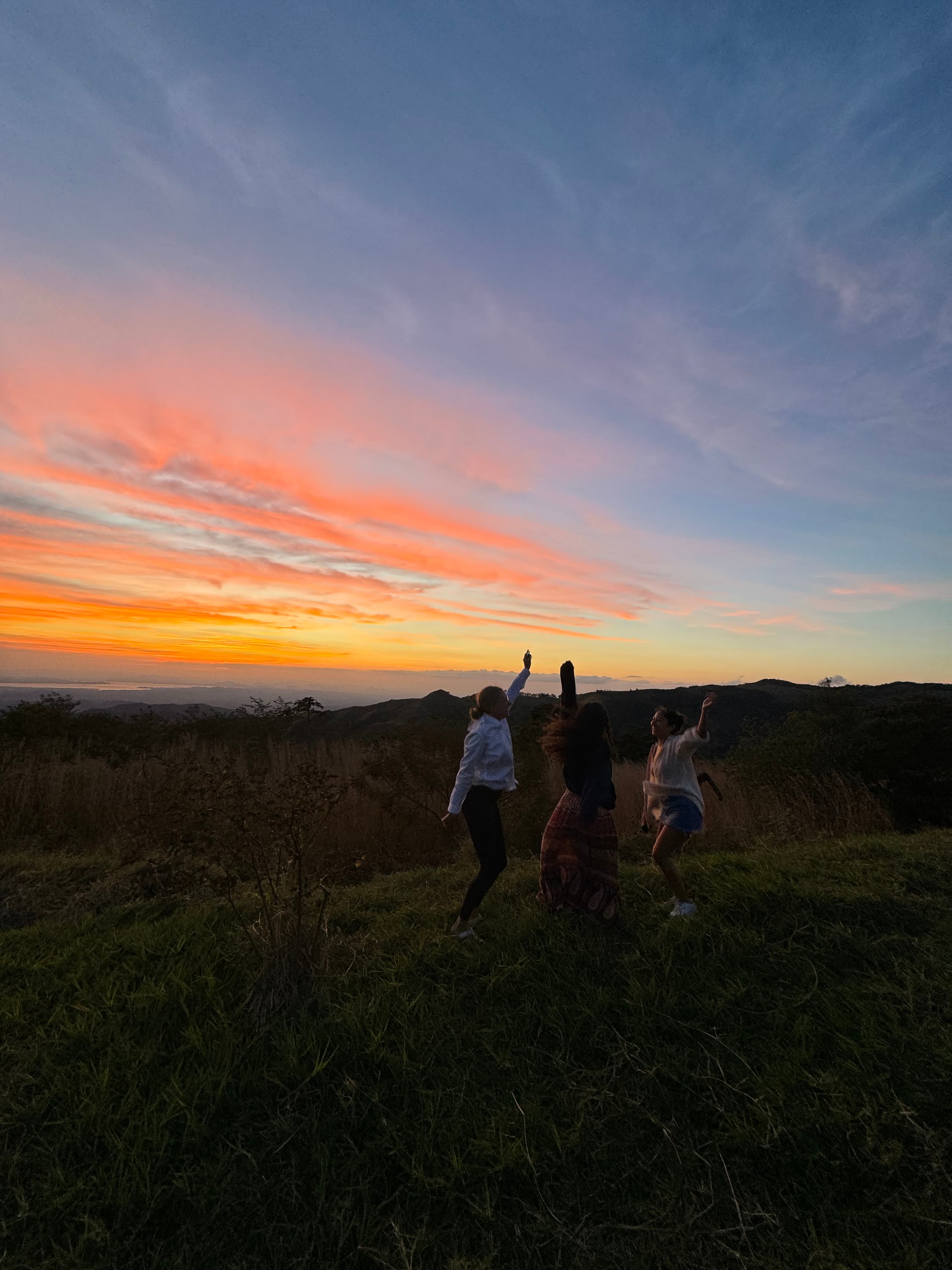 Picture of Samantha outside on a grassy hilltop, frolicking underneath the sunset.