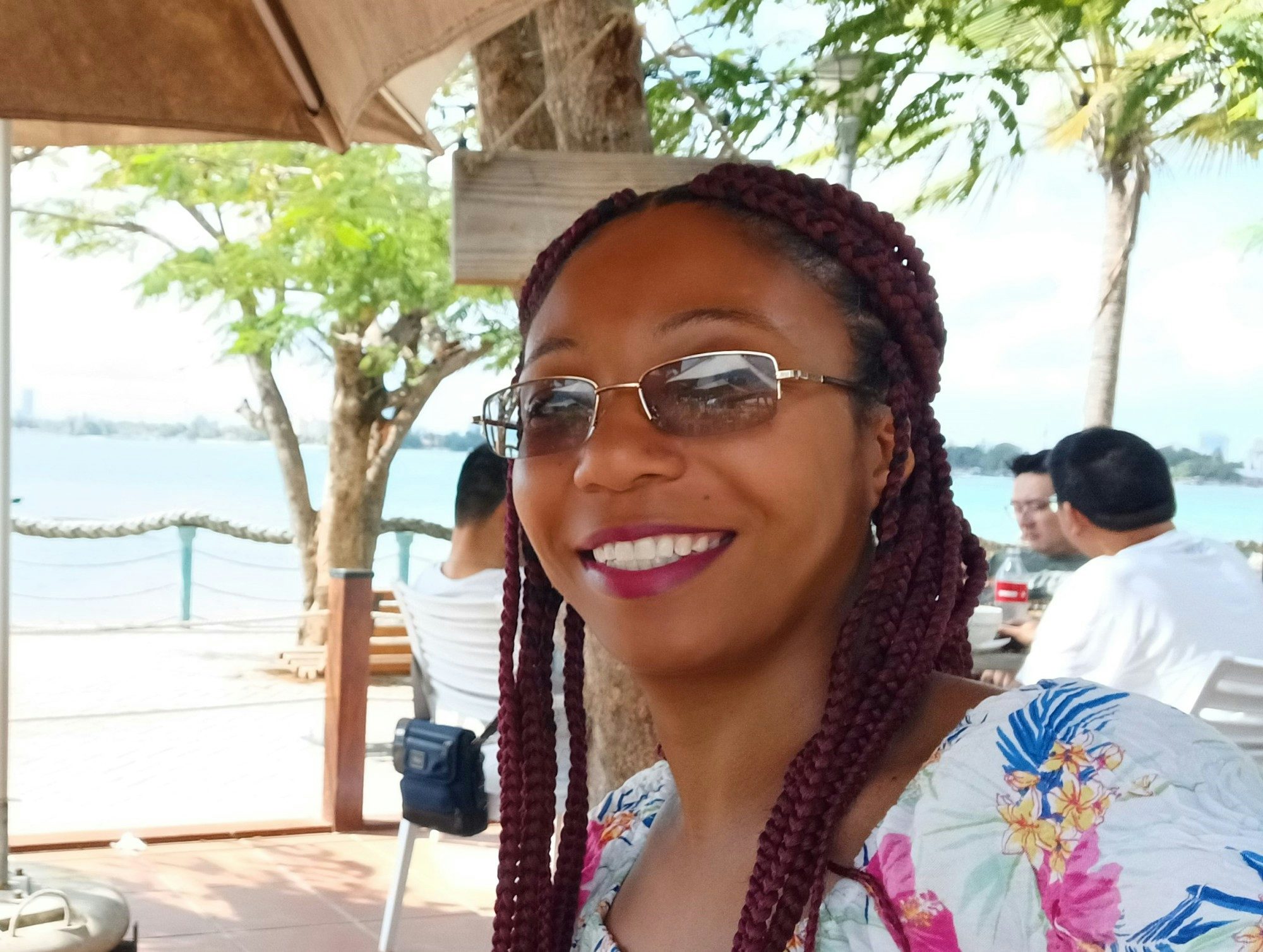 travel advisor Angela Chalmers wears a colorful printed top and sunglasses at a oceanside restaurant