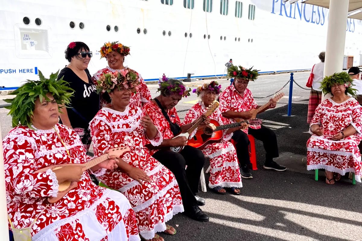 A group of individuals is seen wearing bright red attire with white floral patterns, which appears to be traditional or festive clothing.