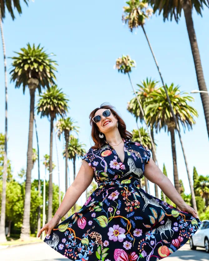 Posing for a picture in floral dress in front of palm trees