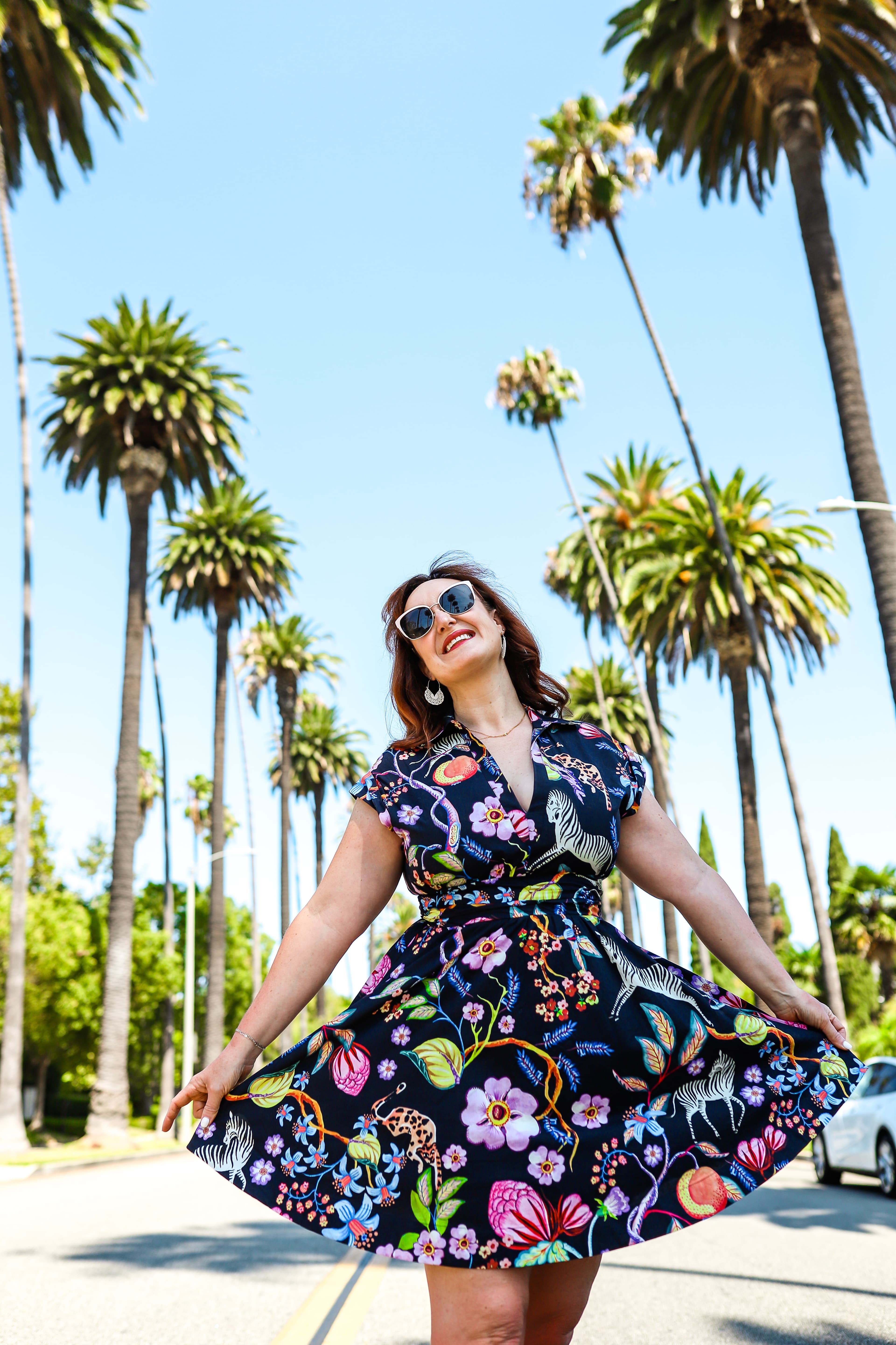 Posing for a picture in floral dress in front of palm trees