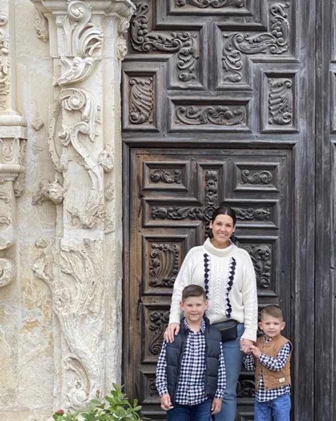 Kimberlie posing for a picture with two children in front of a large wooden door.