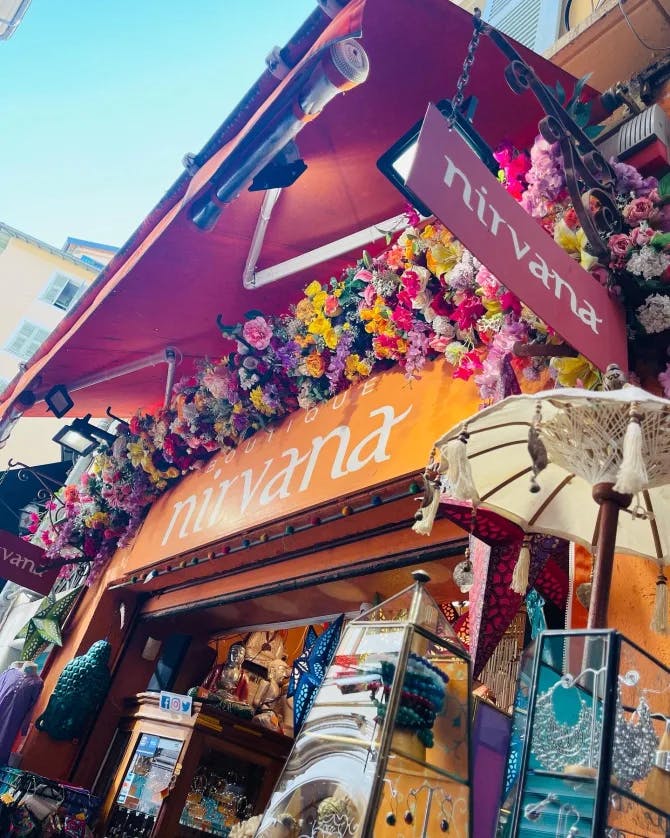 A colorful boutique with a parasol and faux flowers lined up for sale