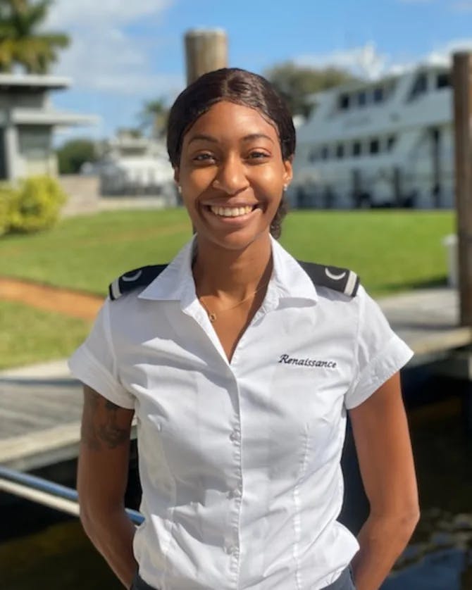 Jazmin Paige posing in her deck hand uniform with yachts in the background. 