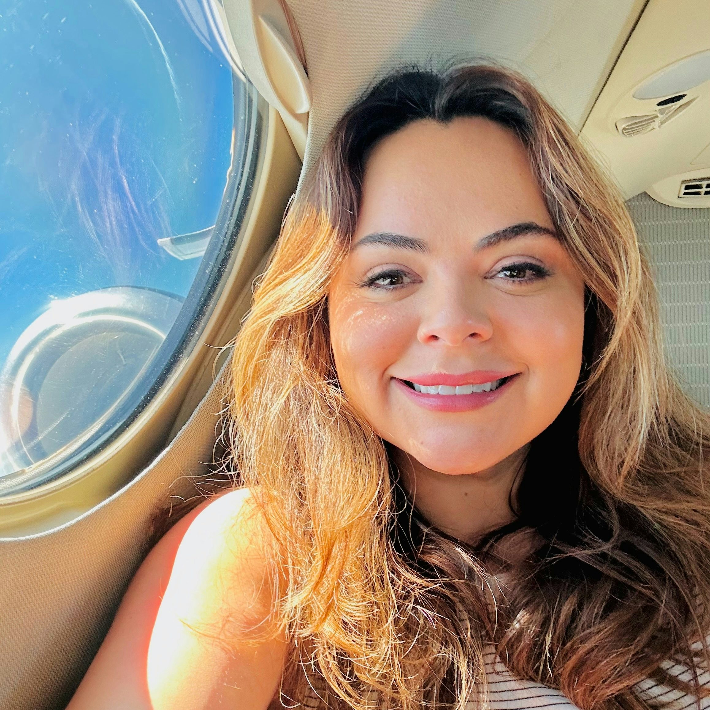 Travel Advisor Erica Villarreal smiling in front of an airplane window.
