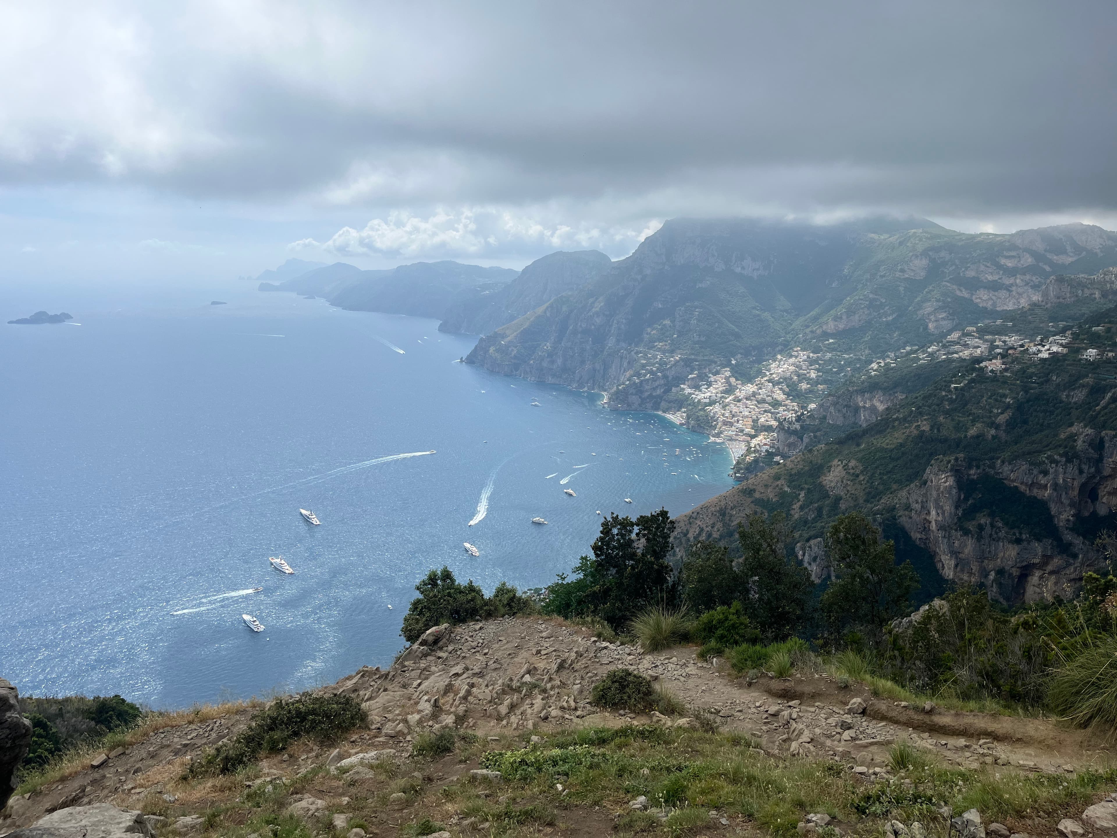 An aerial view of the Amalfi Coast with a dirt path, mountain range and sea in the distance