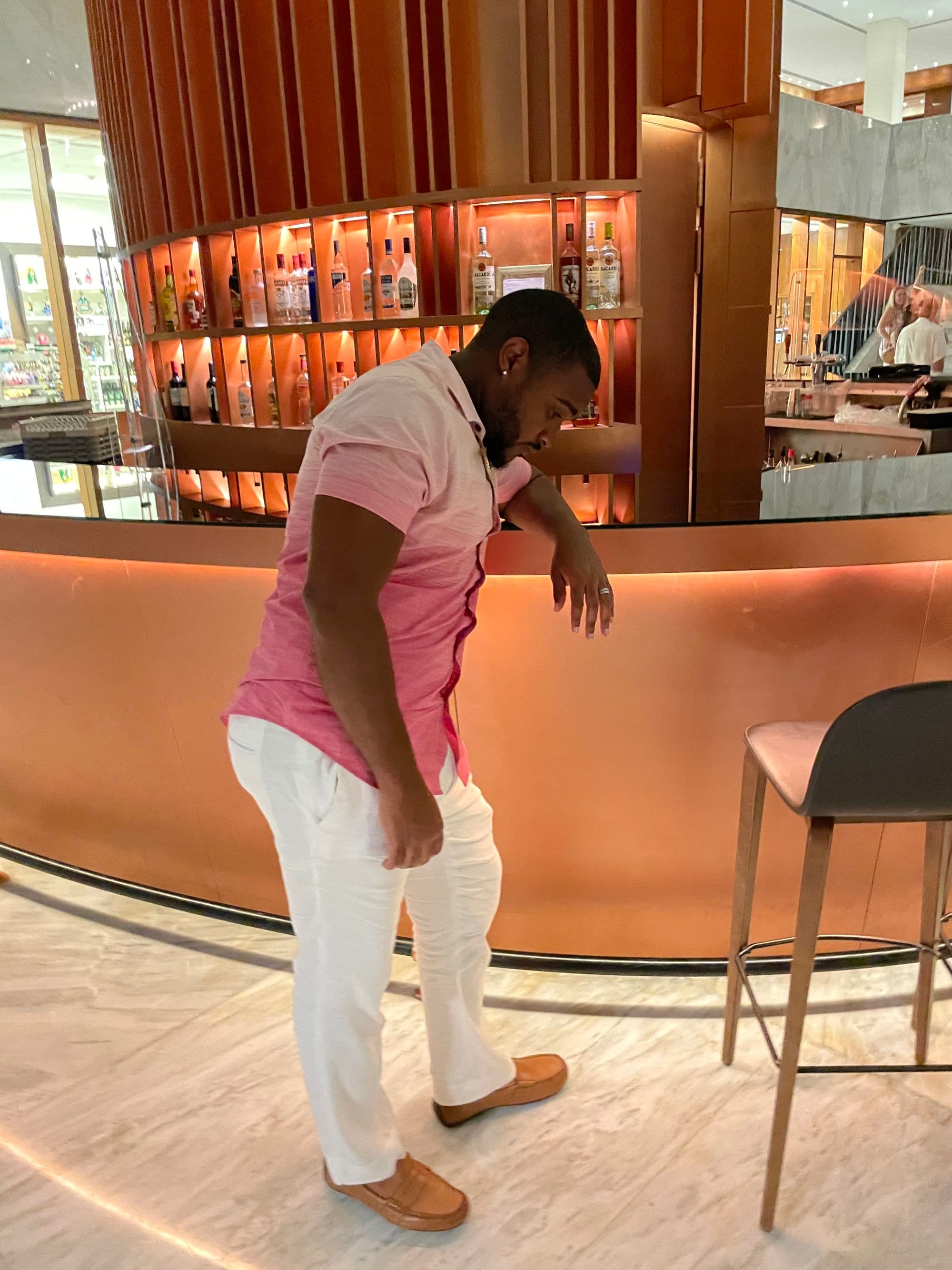 Travel advisor in pink shirt standing at a bar.