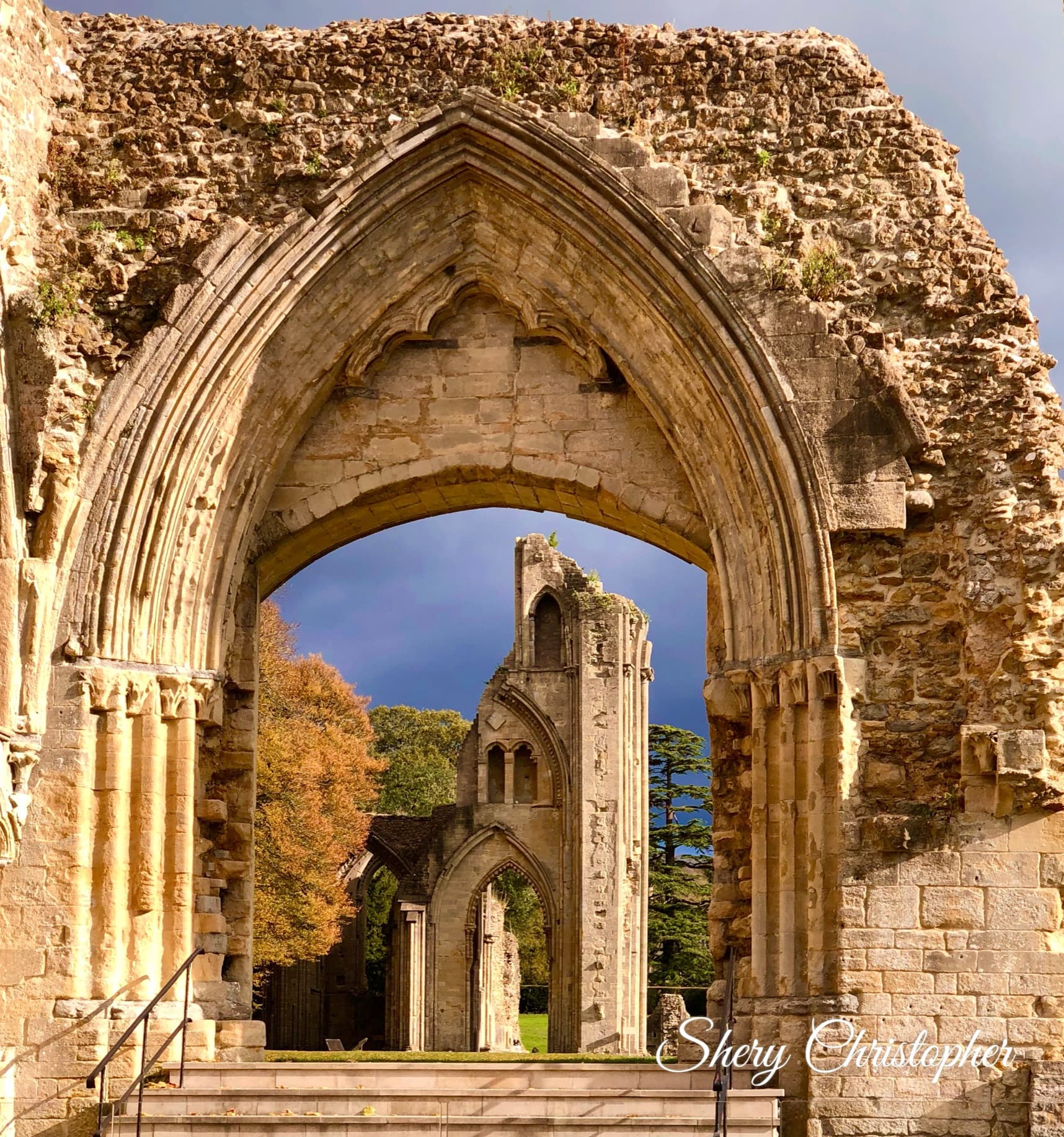 Picture of Glastonbury Abbey with trees and stormy clouds in the background