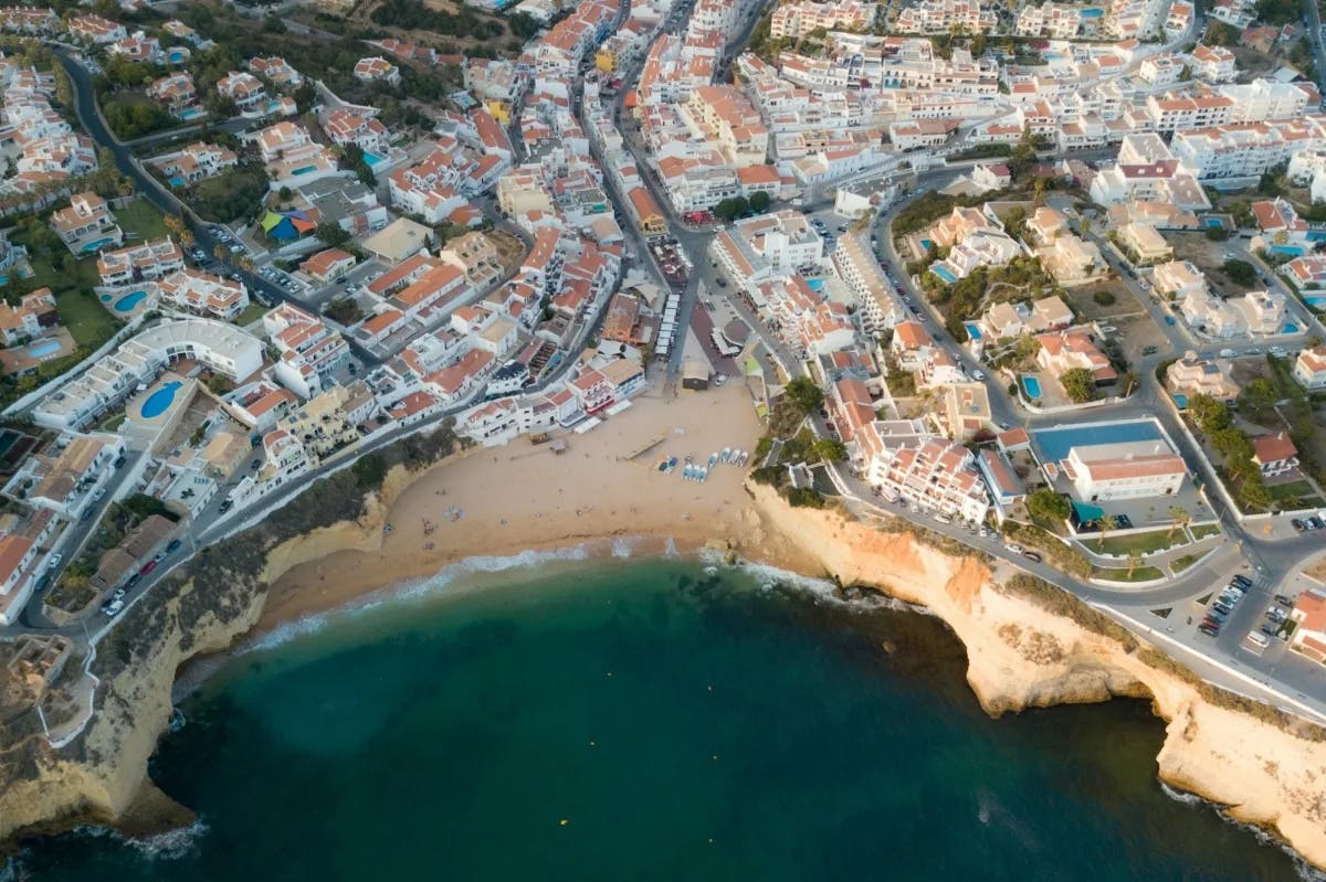 A drone-view spots a small beach amidst a variety of historic structures, luxury hotels and more in the Algarve