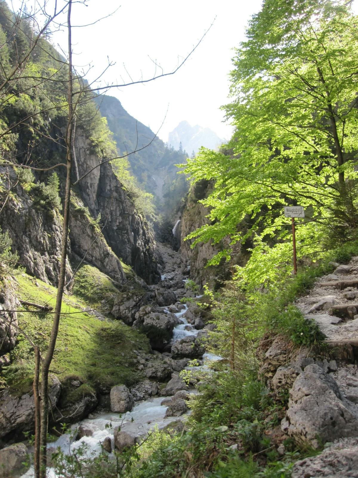A scenic area with green trees and a stream of water through a rocky valley