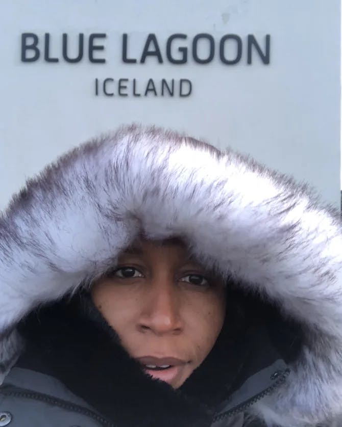 Kenya wearing a winter jacket and posing for a selfie in front of the Blue Lagoon in Iceland
