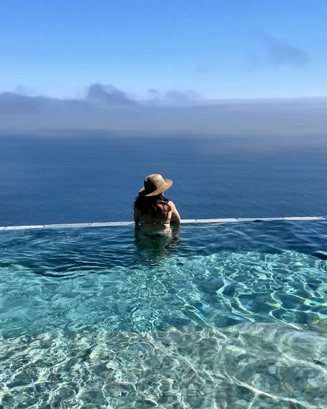 Picture of Arianna in an infinity pool looking over the edge into the distance of the ocean.