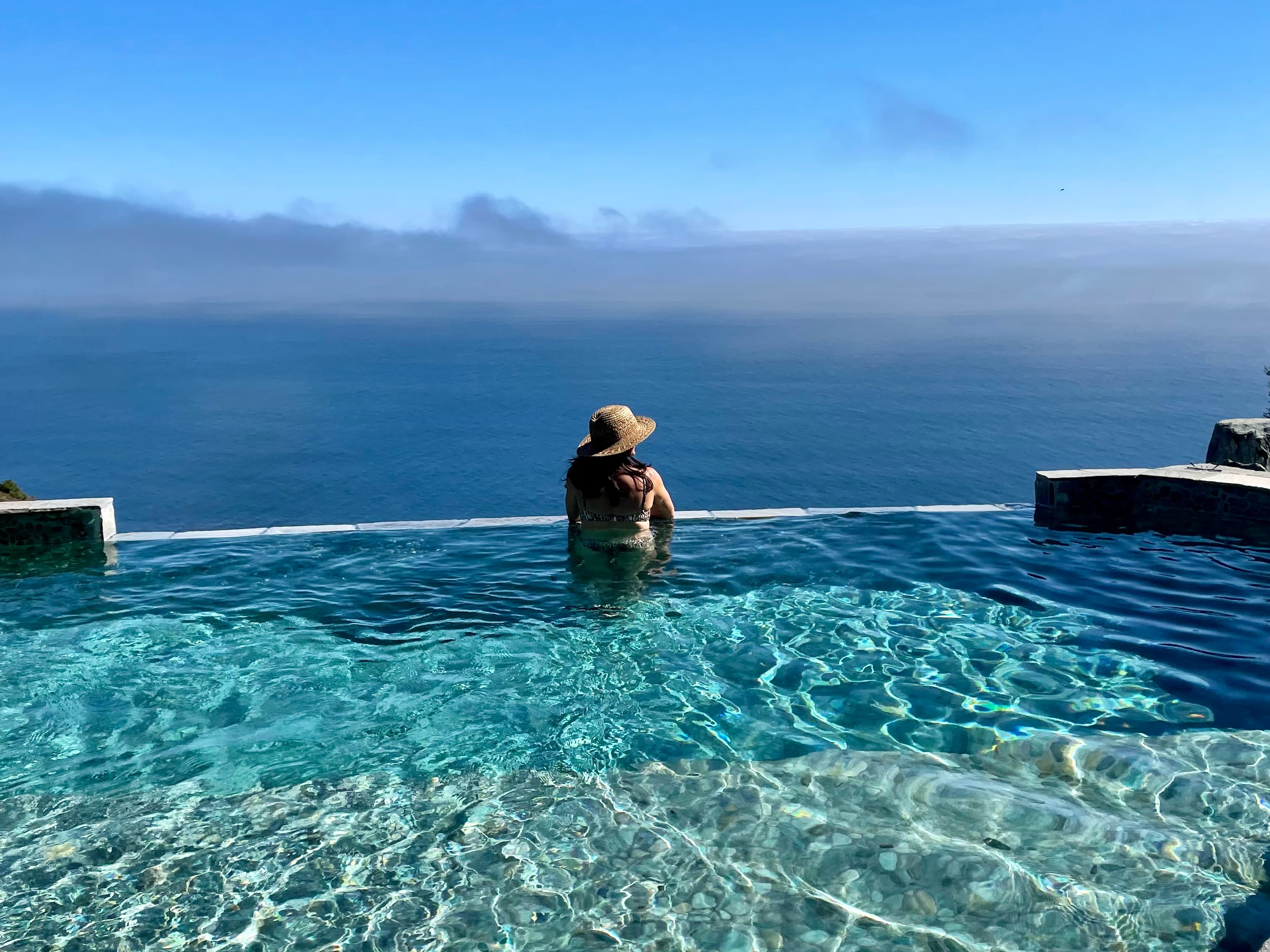 Picture of Arianna in an infinity pool looking over the edge into the distance of the ocean.