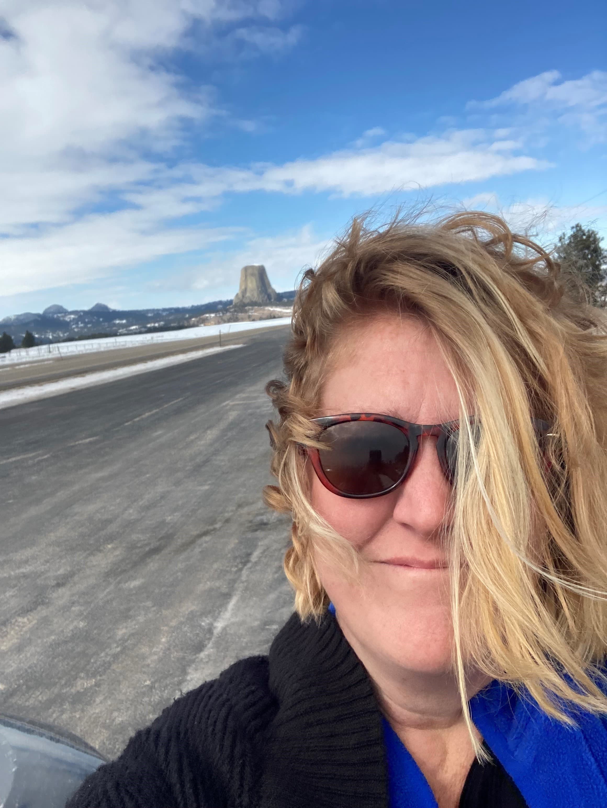Travel advisor posing with glasses with a road behind