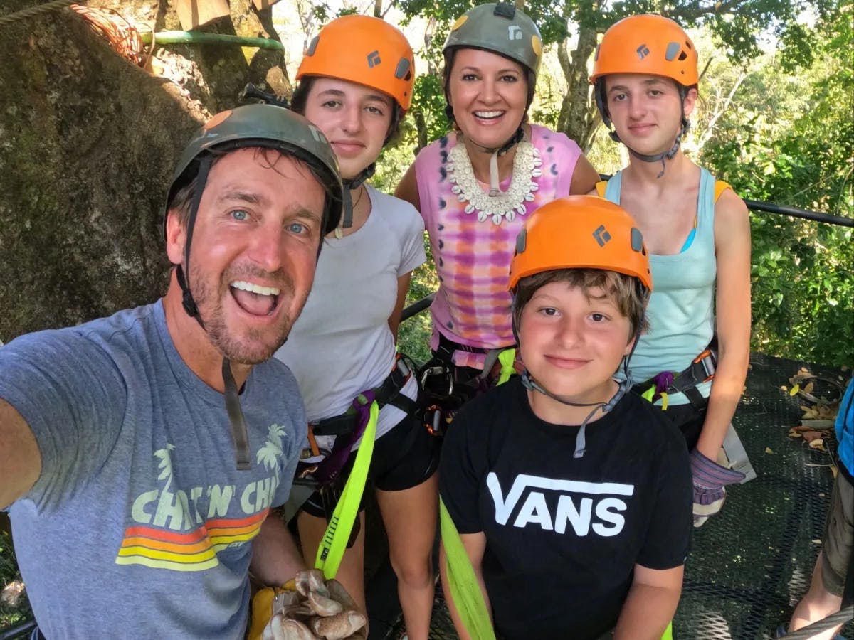 A group of people ready to zipline wearing orange and gray helmets