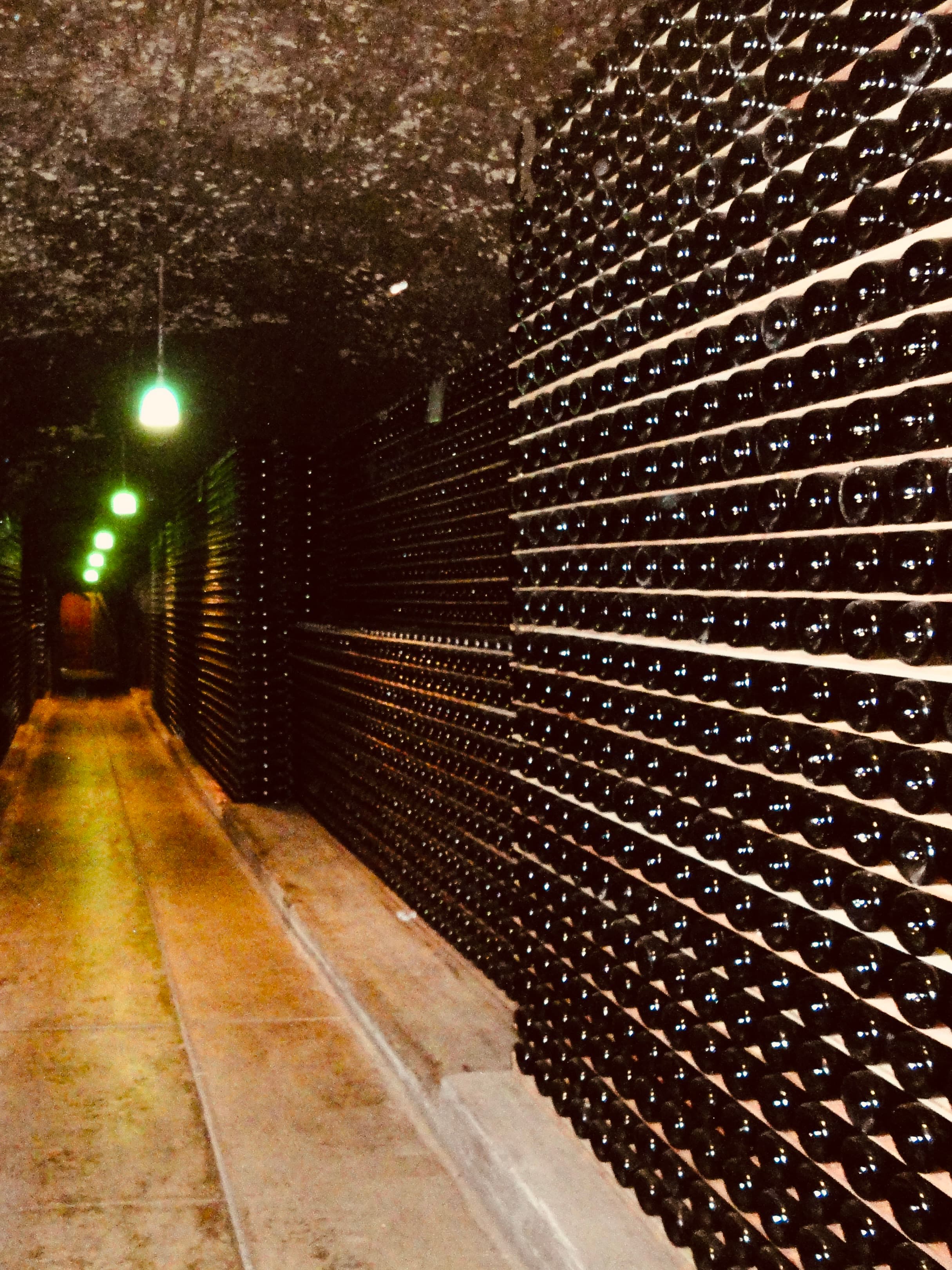 A wine cellar with a long, concrete hallway full of wine bottles.