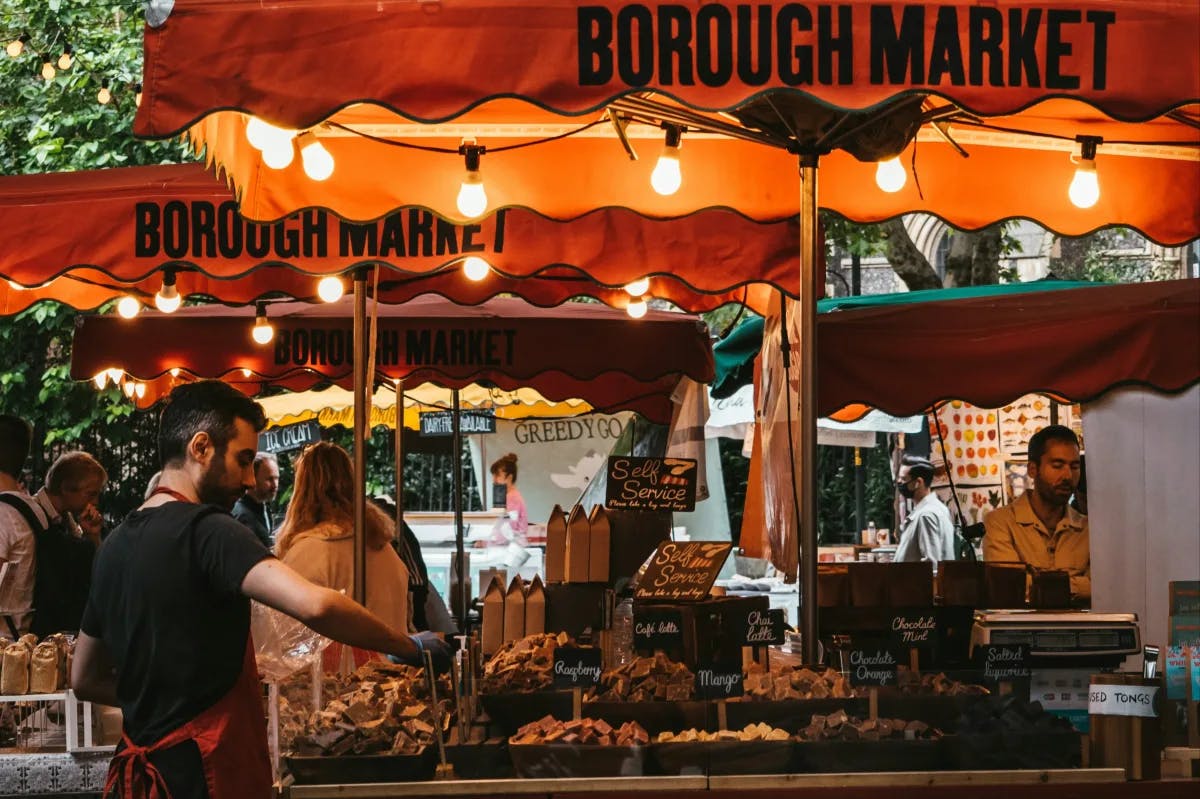 An outdoor food stall with orange umbrellas reading "Borough Market"