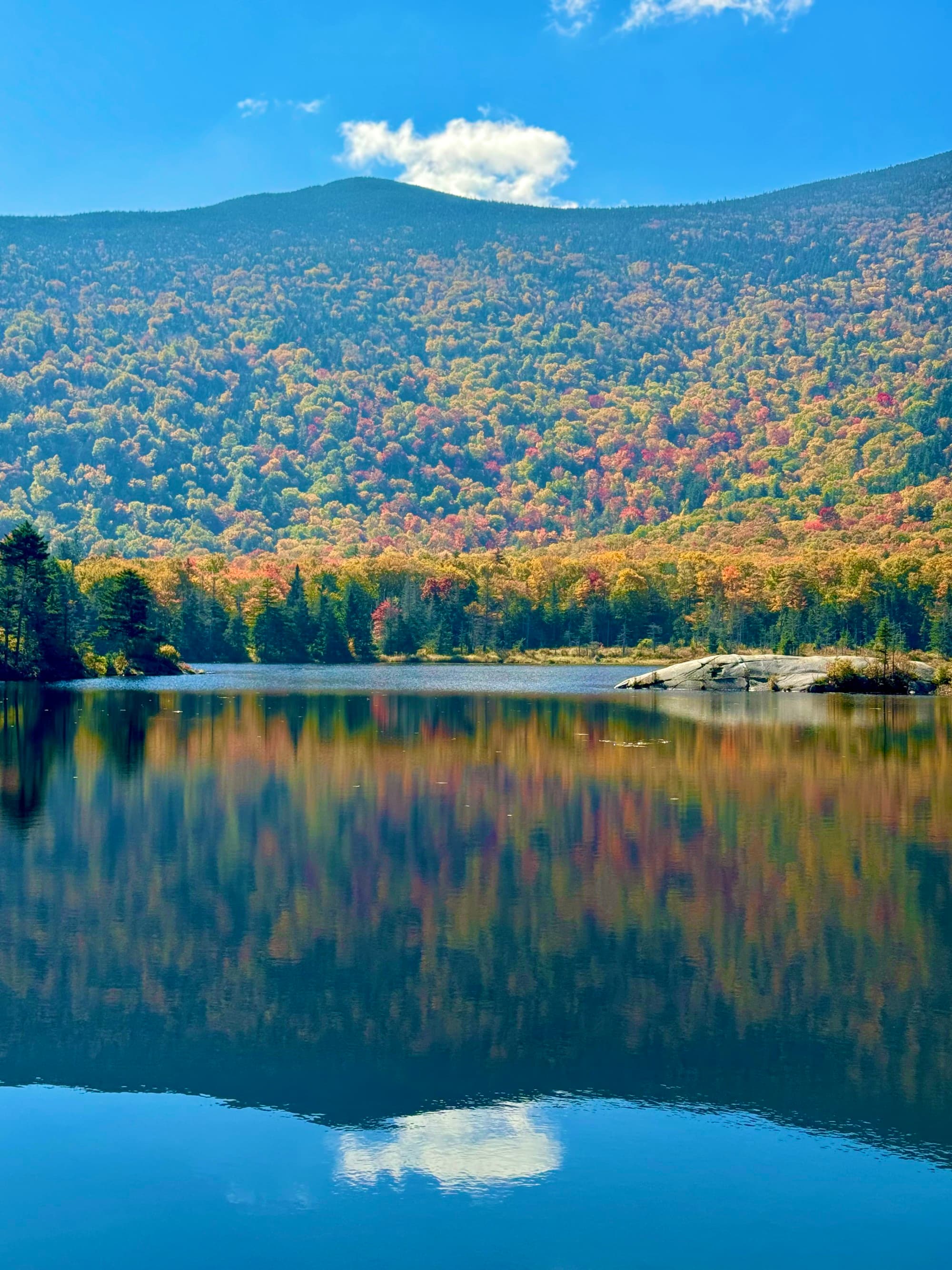 A clear lake with reflection of mountains and trees.