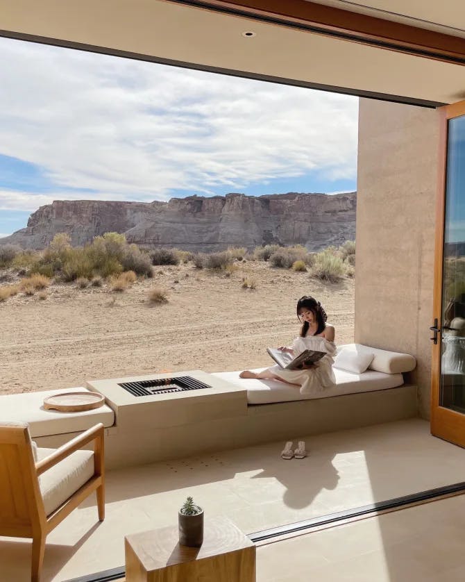 Jessica reading a book on a sofa in a luxurious room that overlooks the open desert 