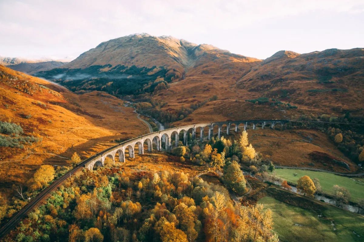 Aerial view of the Glenfinnan Viaduct in the Scottish Highlands with fall foliage in full swing