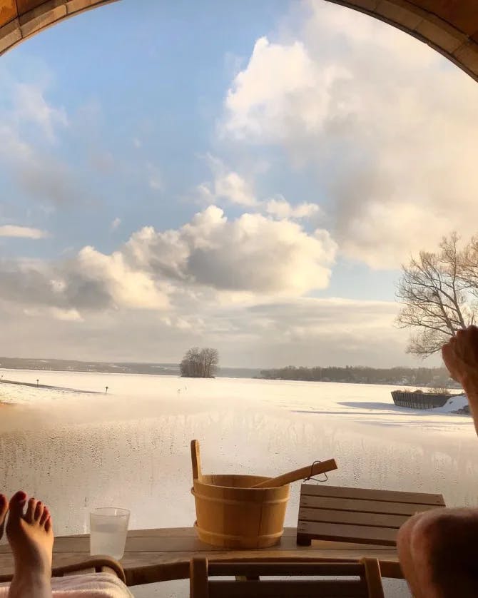 Travel advisor posing inside a sauna looking out of a window to a snowy field