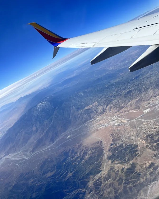 Picture of an airplane wing flying over a mountainous terrain