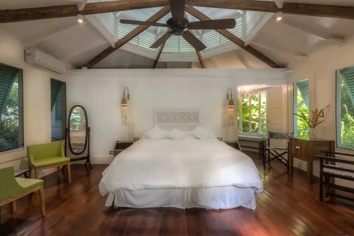 Plush linens, hardwood floors and furniture, and windows that open up to the surrounding jungle define this luxe room at Hotel Aguas Claras