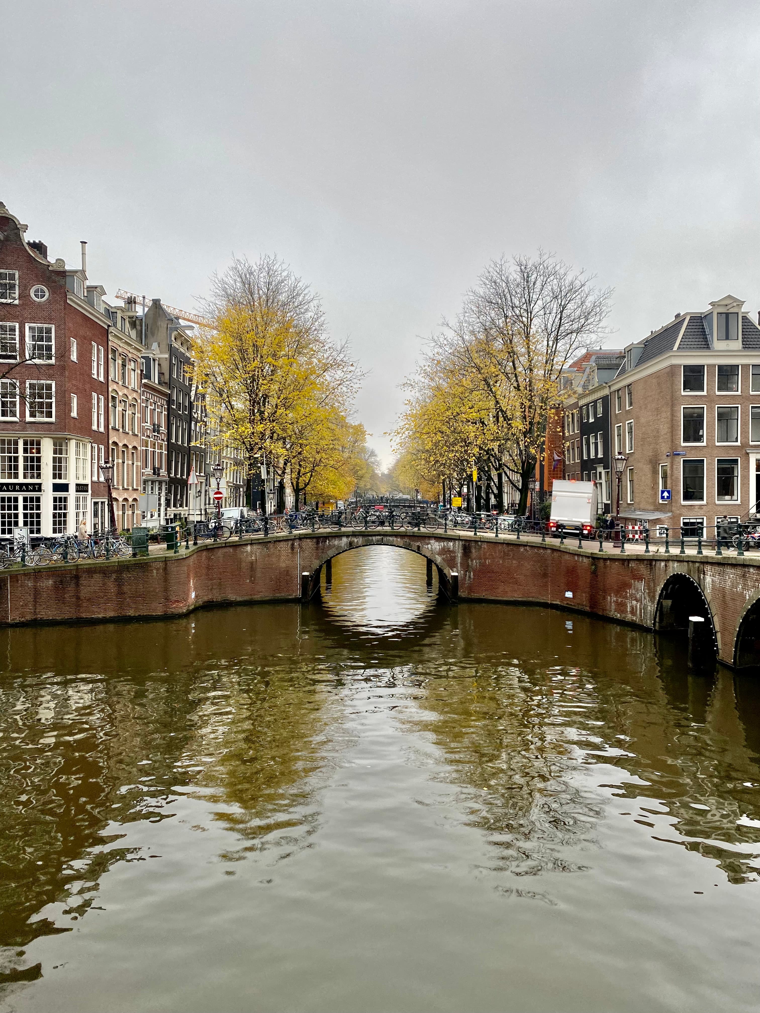 Picture of bridge over a canal in Europe with trees and buildings in the background on each side