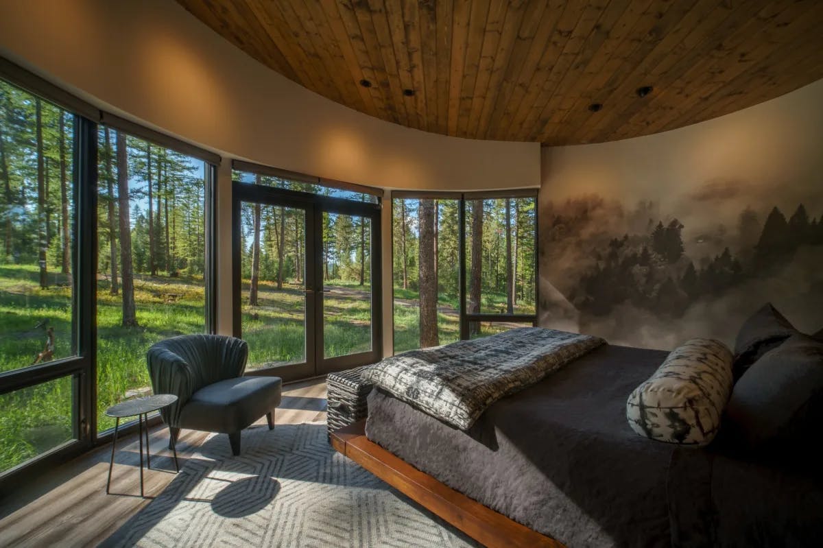 a bed in a cozy glass-walled room with a wooden ceiling