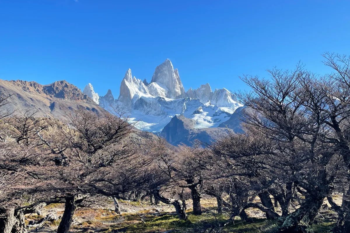 The sky is clear with minimal clouds, casting bright sunlight that illuminates the entire scene and creates contrasts between light and shadow on the mountains.