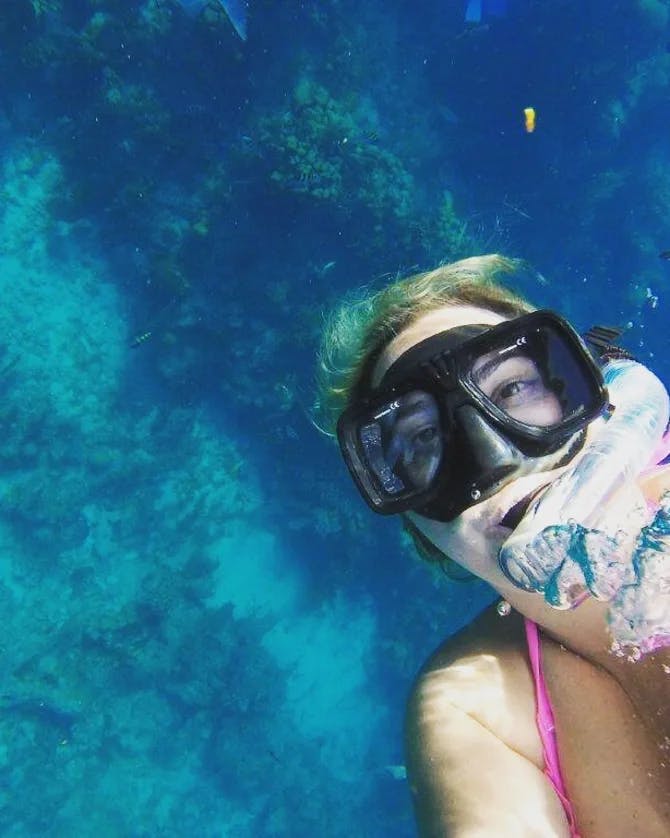 Ashley wearing scuba gear underwater with a striped fish in the background