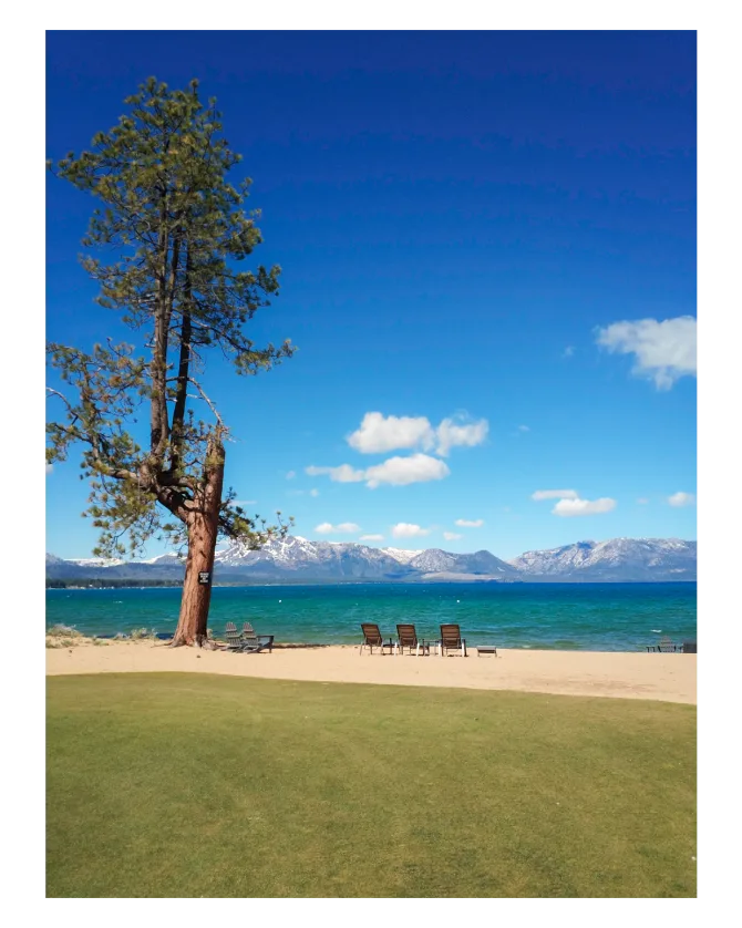 Picture Lake Tahoe with a beautiful beach and the mountains in the distance. 