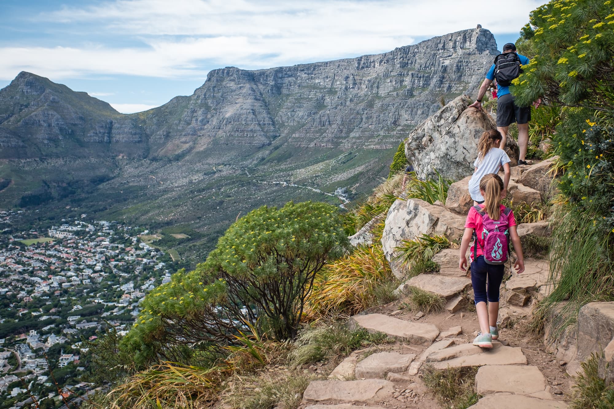 A man with two kids on a hiking trail.
