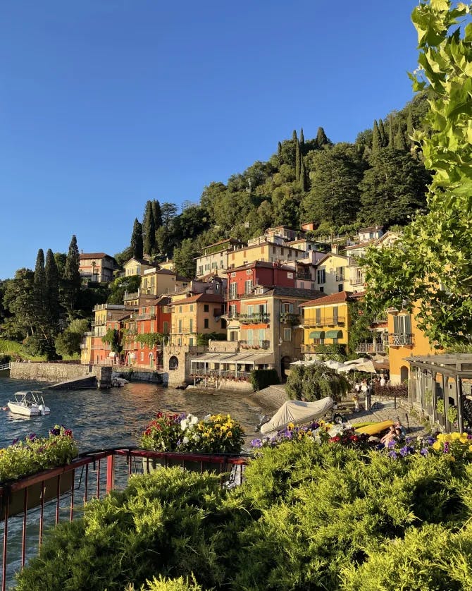 Picture of colorful houses on Lake Como at golden hour surrounded by green trees and water
