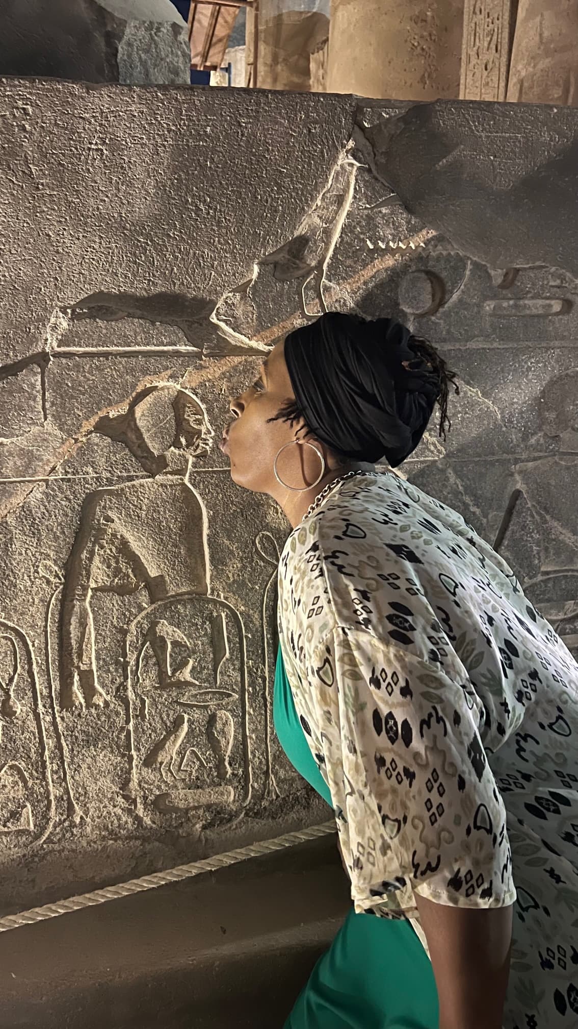 angela kissing a stone with hieroglyphics on it