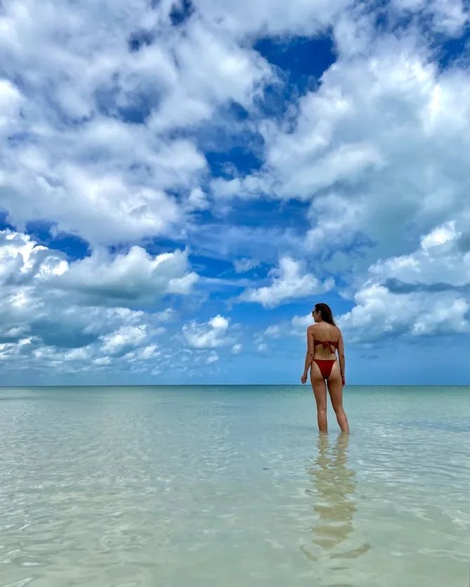 Travel advisor standing in the ocean with a beautiful view of the water and clouds. 