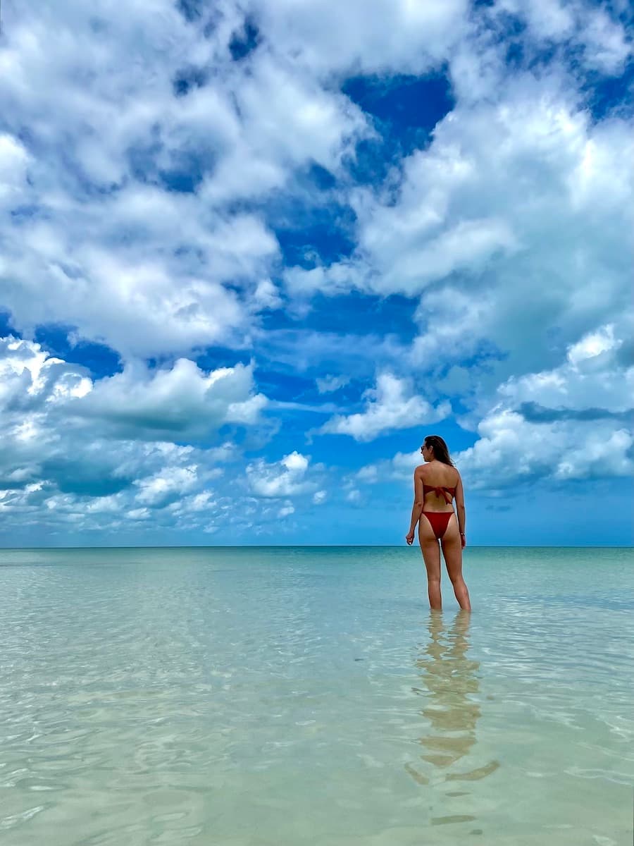 Travel advisor standing in the ocean with a beautiful view of the water and clouds.