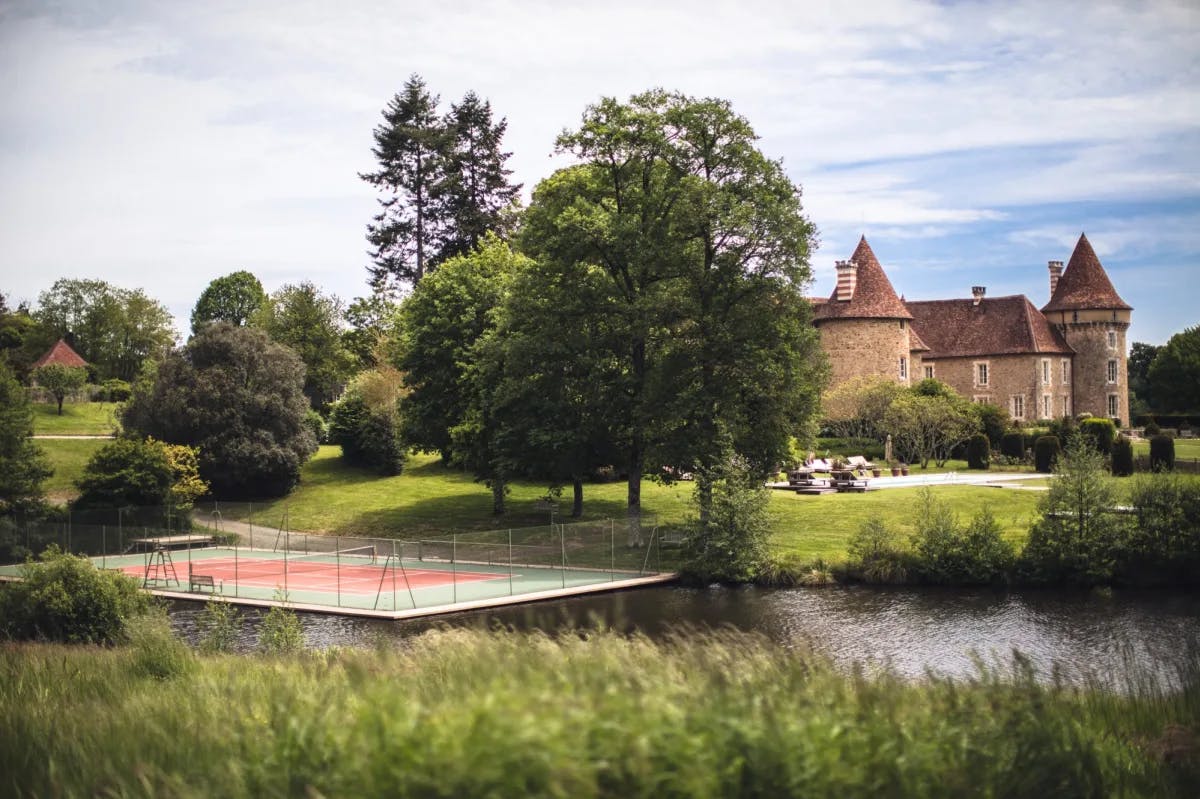 a floating tennis court on a pond near a stone castle in the countryside