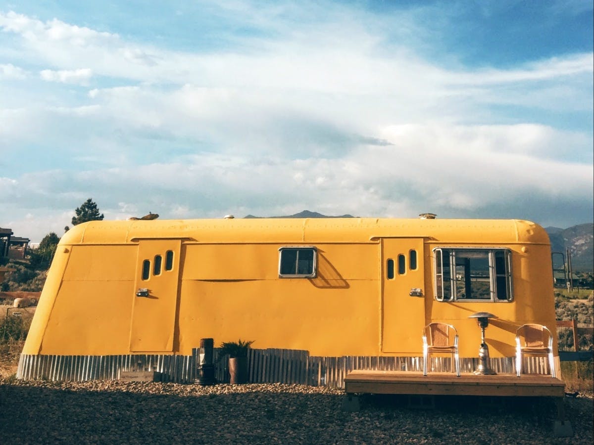 Yellow small house parked in desert in New Mexico on a sunny day.